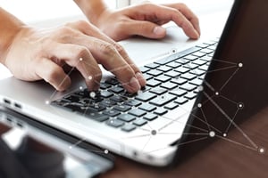 Close up of business man hand working on laptop computer with social network diagram on wooden desk as concept