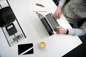 person working on laptop at desk with calculator near by